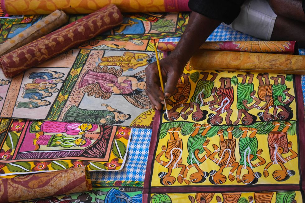 A chitrakar is painting a patachitra inside a trade fair in Kolkata, India.