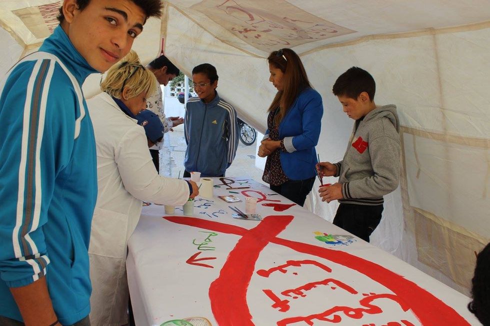 A group of people collectively work on painting an informational banner.