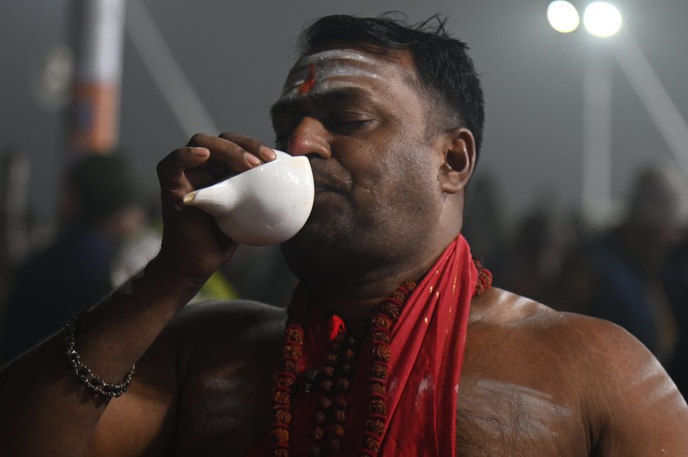 A holy man blows a conch shell to signal the start of the spiritual ceremony
