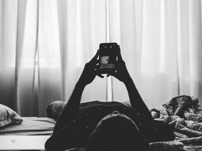 A man lying on a bed with a smartphone