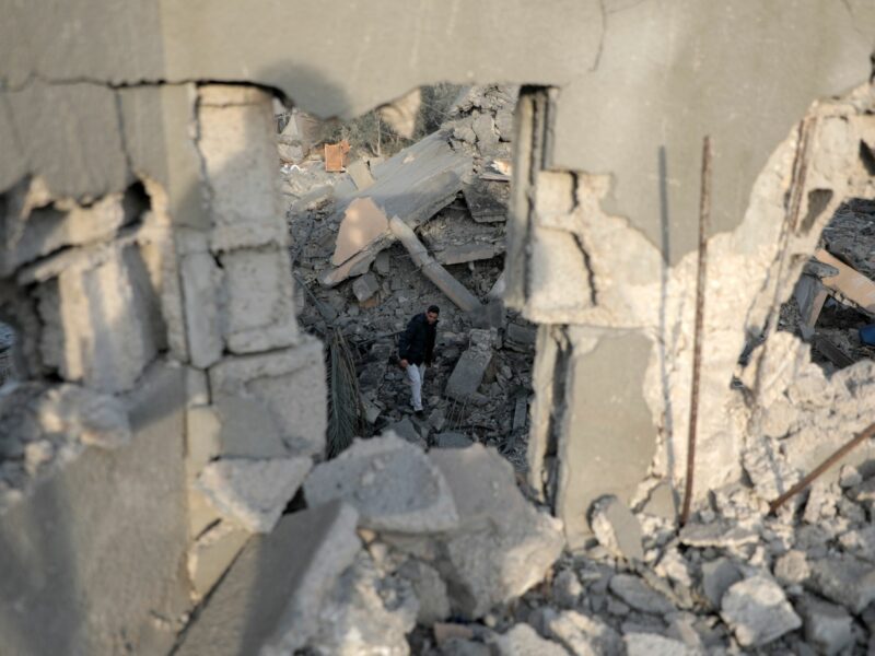 A Palestinian man is framed by the structure of a destroyed building