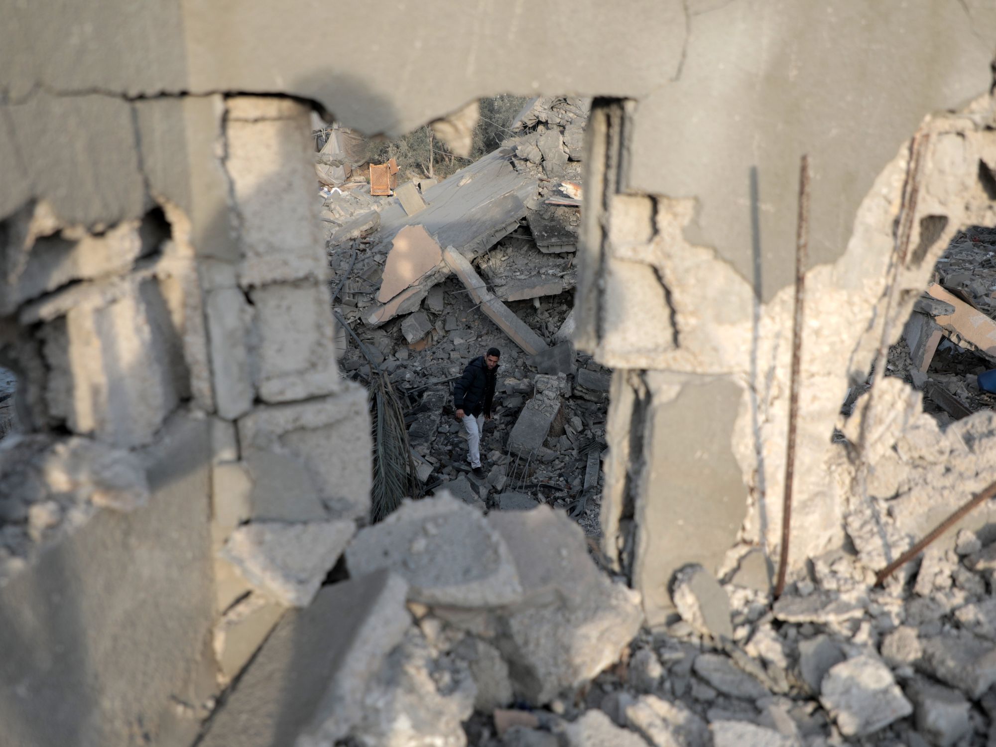 A Palestinian man is framed by the structure of a destroyed building