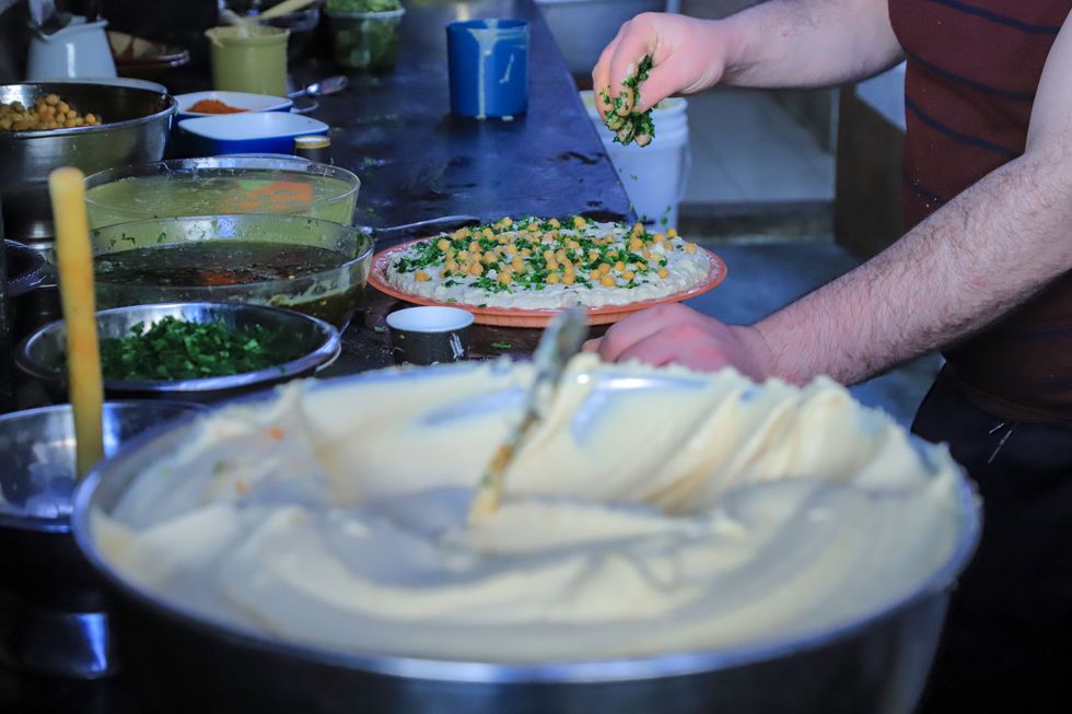 A Palestinian vendor prepares hummus plates at a store before the daily 'iftar' (fast breaking) meal during the Muslim holy month of Ramadan in Gaza City on March 28, 2023.