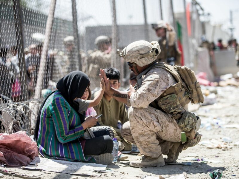 A U.S. Marine interacts with Afghan refugees at the Evacuation Control Center at Kabul's airport backin August 2021.