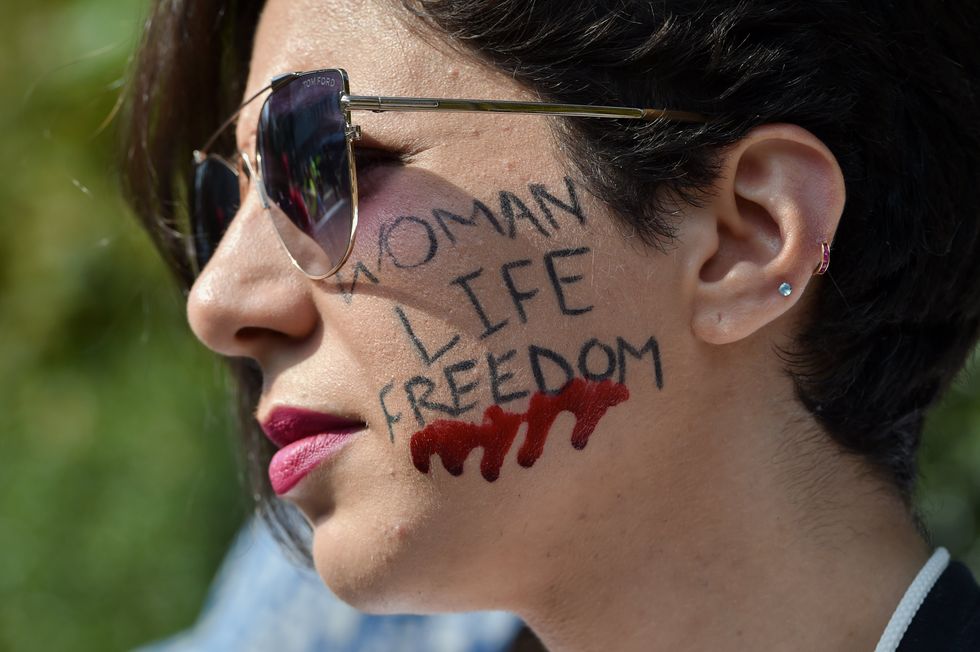 A woman with the slogan "Woman Life Freedom" painted on her cheek during a march to commemorate the first anniversary of Mahsa Amini's death in London.
