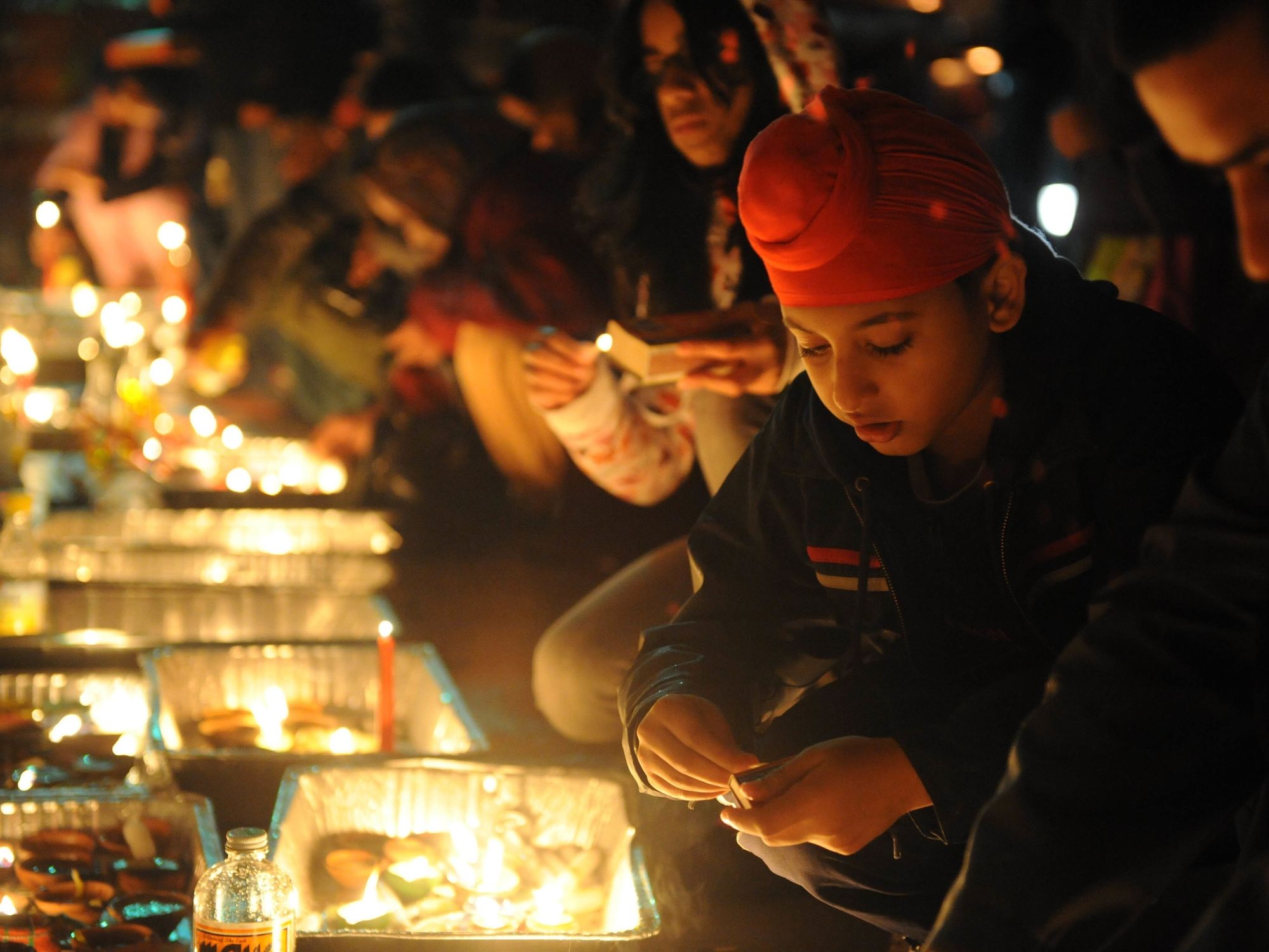 A young boy lights a candle at a Diwali celebration