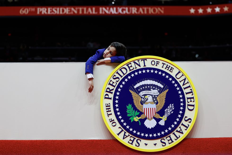 An Indian American boy rests his head on a balcony, under which is the seal of the President of the United States