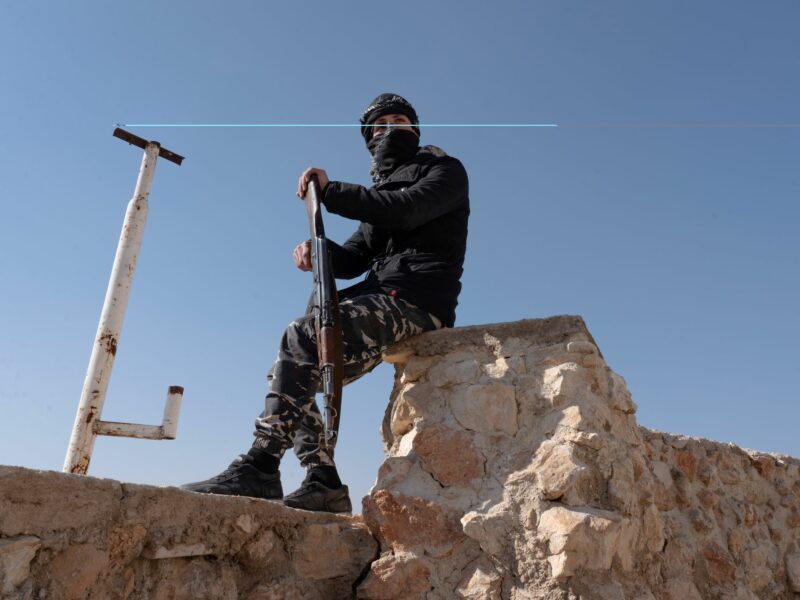 HTS officer with his riflle sitting outside Sednaya Prison.