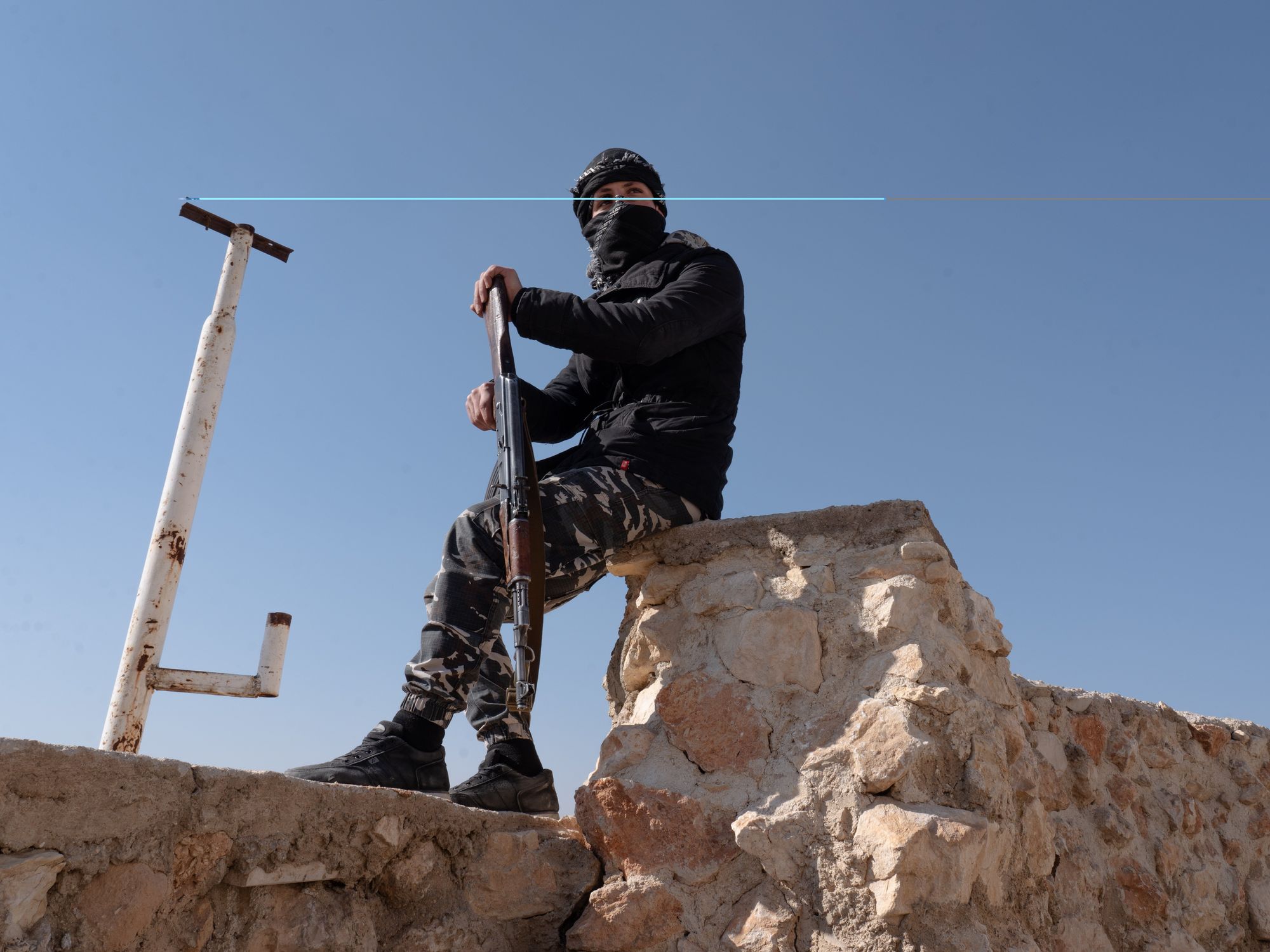 HTS officer with his riflle sitting outside Sednaya Prison.