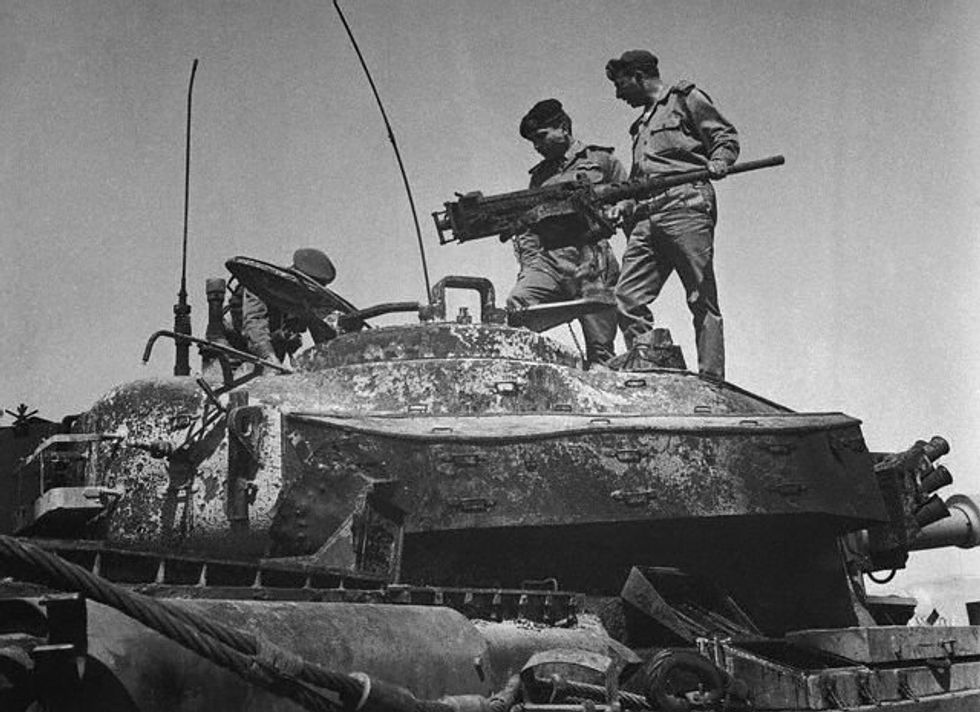 Hussein and other soldiers stand on an abandoned Israeli tank. The photo is in black and white.