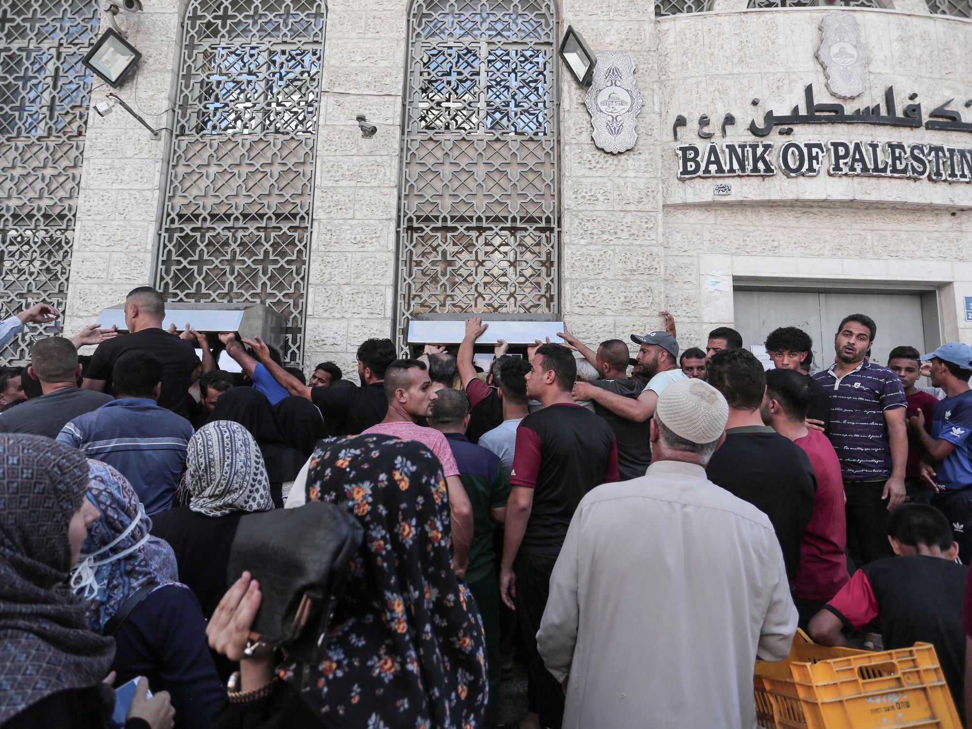 Palestinian Authority employees wait to receive their salaries from an ATM, outside a Palestine Bank in Khan Younis in the southern Gaza Strip