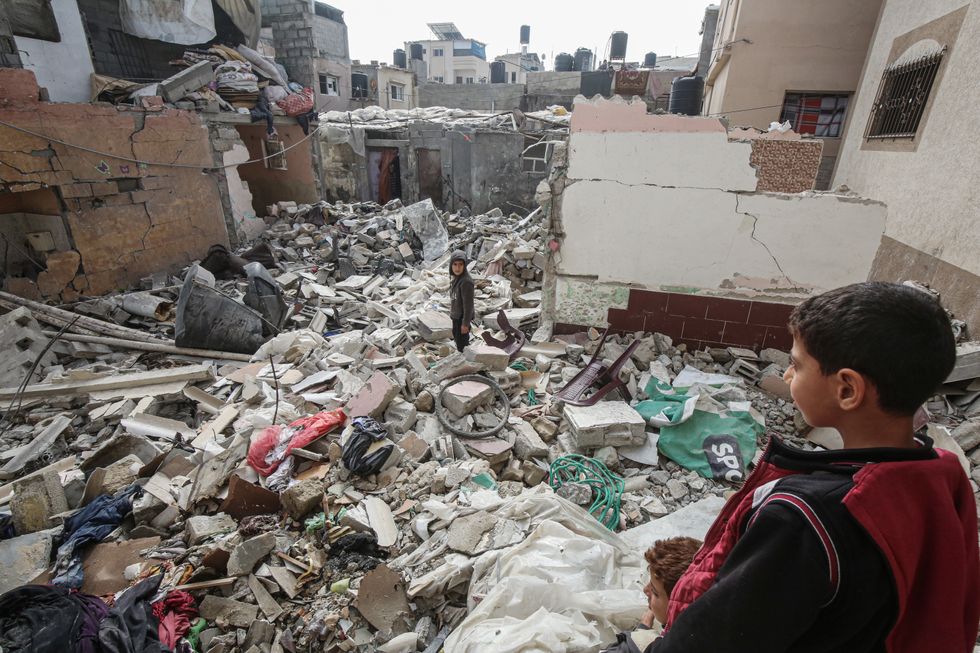 Palestinian residents inspect the area amid the rubble of destroyed buildings following an Israeli airstrike on the Khatib family