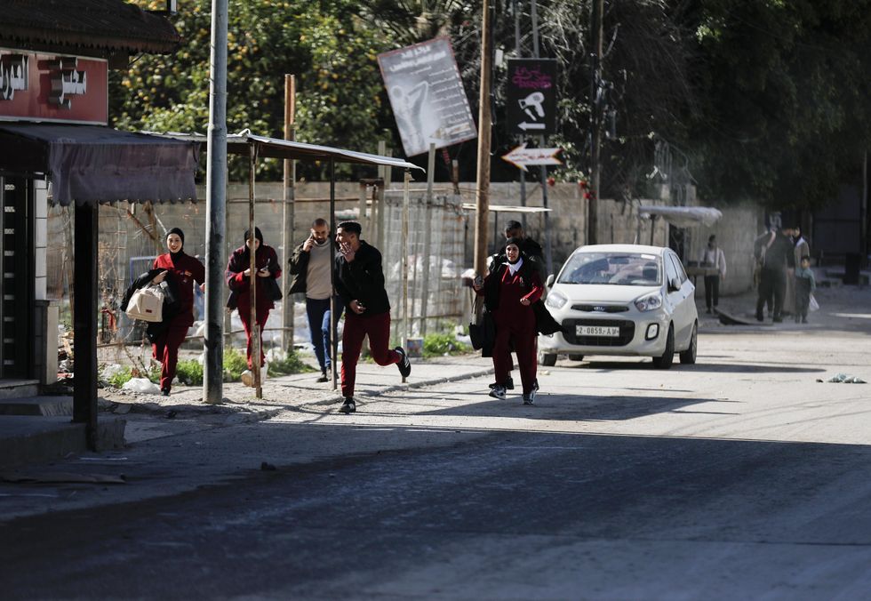 People run to take cover during an Israeli military operation in the West Bank city of Jenin, on Jan. 21, 2025.
