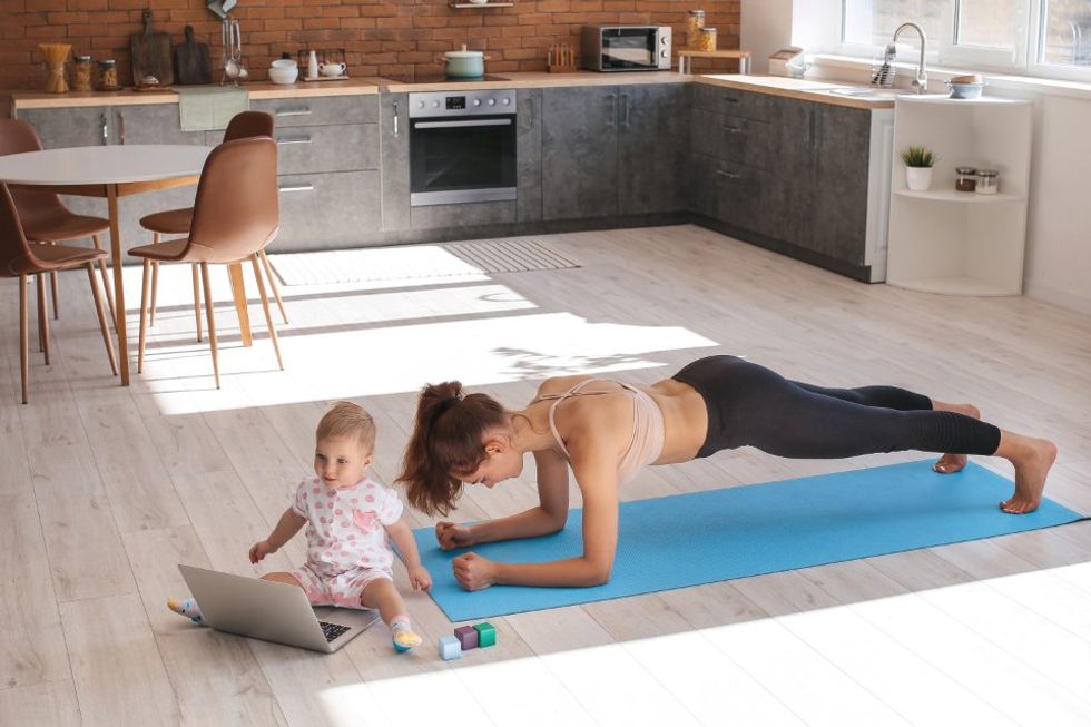 photo of a baby in front of a computer with mom doing yoga