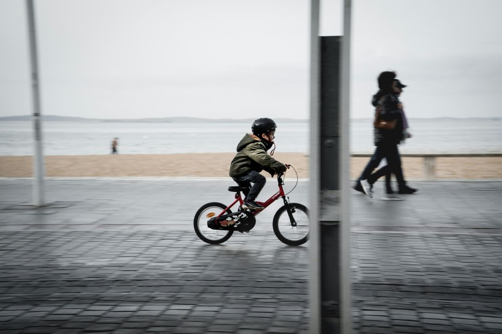 Photo of a kid riding a bike with his helmet on