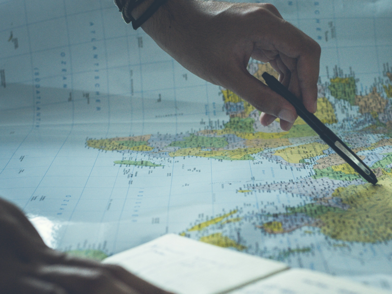 Photo of a person pointing at a paper map with a black pen
