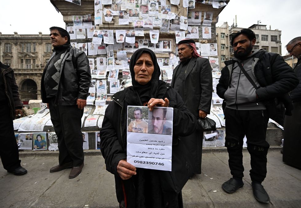 photo of a woman holding a paper with her son's photo and information
