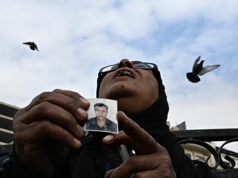 Photo of a woman holding a small picture of her son with birds flying