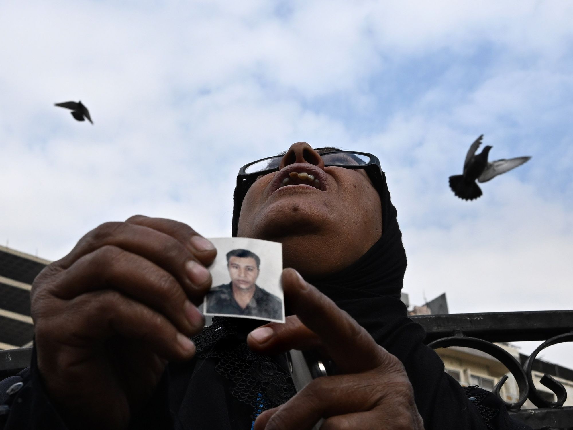 Photo of a woman holding a small picture of her son with birds flying