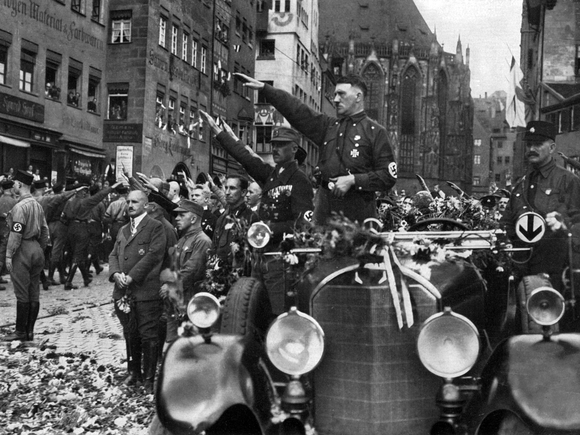 Photo of Adolf Hitler standing on a motorcade, saluting SS members during a Nazi Party Congress in Nuremberg in December 1927