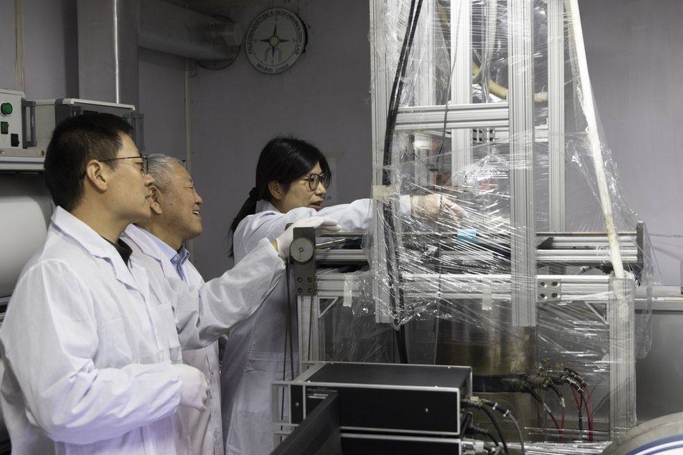 Researchers Cai Shuhui (R), Zhu Rixiang (C) and Qin Huafeng place rock sample collected by China's Chang'e-6 lunar probe at a lab of the Institute of Geology and Geophysics under the Chinese Academy of Sciences