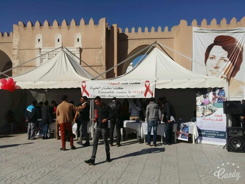 Two information tents with resources for preventing and mitigating AIDS are set up in front of a bigger wall