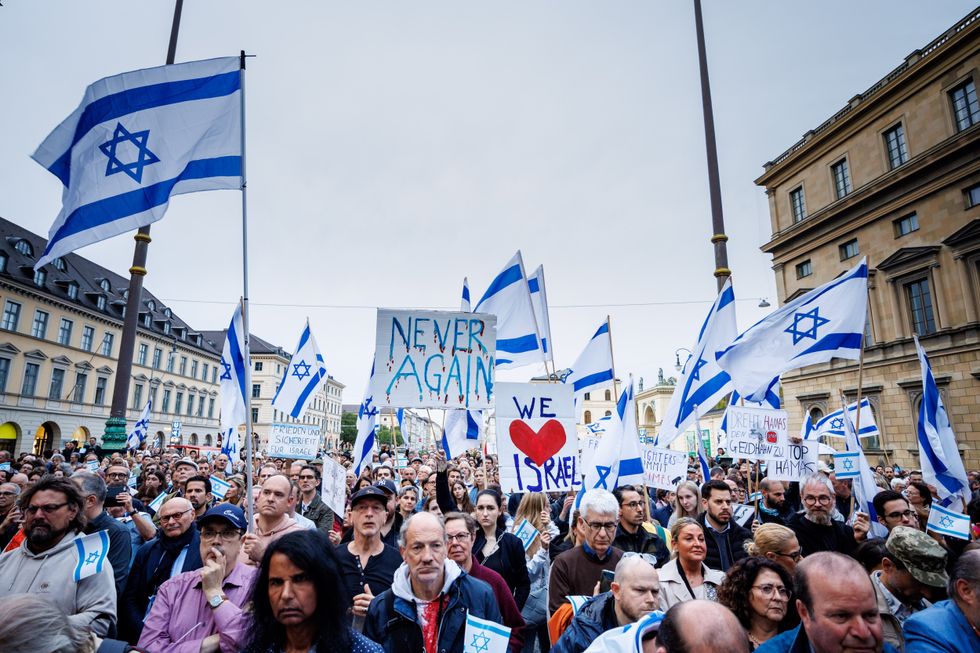 09 October 2023, Bavaria, Munich: Numerous participants hold their signs with inscriptions such as ''Never again'' or ''We love Israel'' as well as Israeli flags at a solidarity rally for Israel on Odeonsplatz.