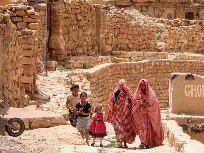 2 women and 3 little girls, walk along what looks like ancient ruines
