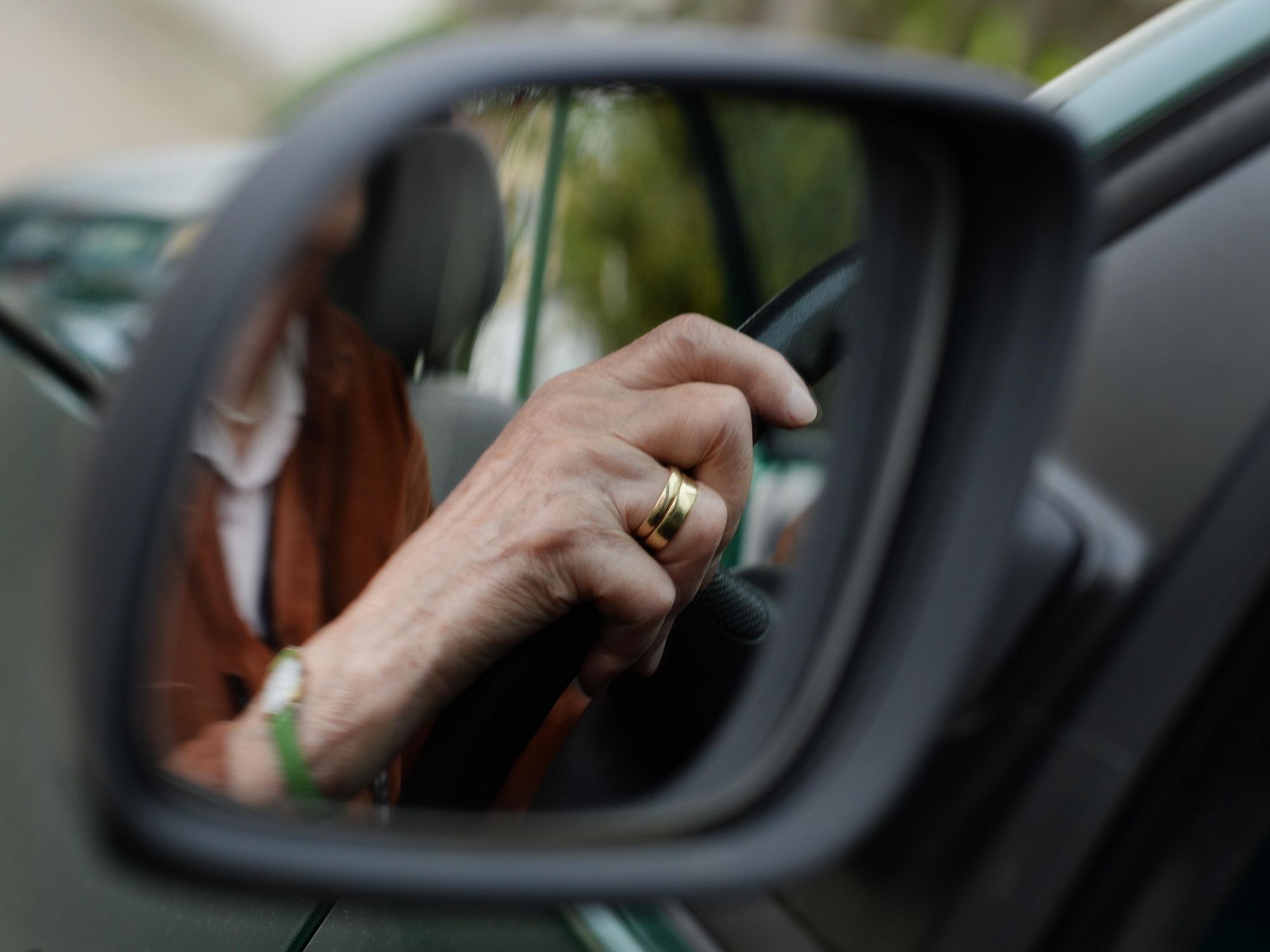 A 84-year-old woman mirrors in the sideview mirror as she is driving her car in Weingarten, Germany