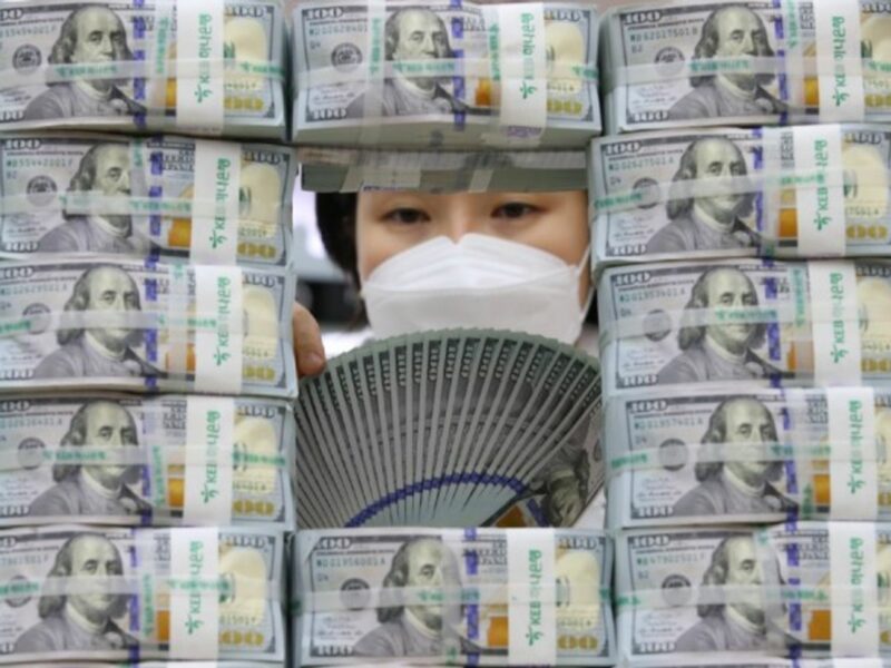 A bank clerk scrutinizes 0 US banknotes in Seoul, South Korea.
