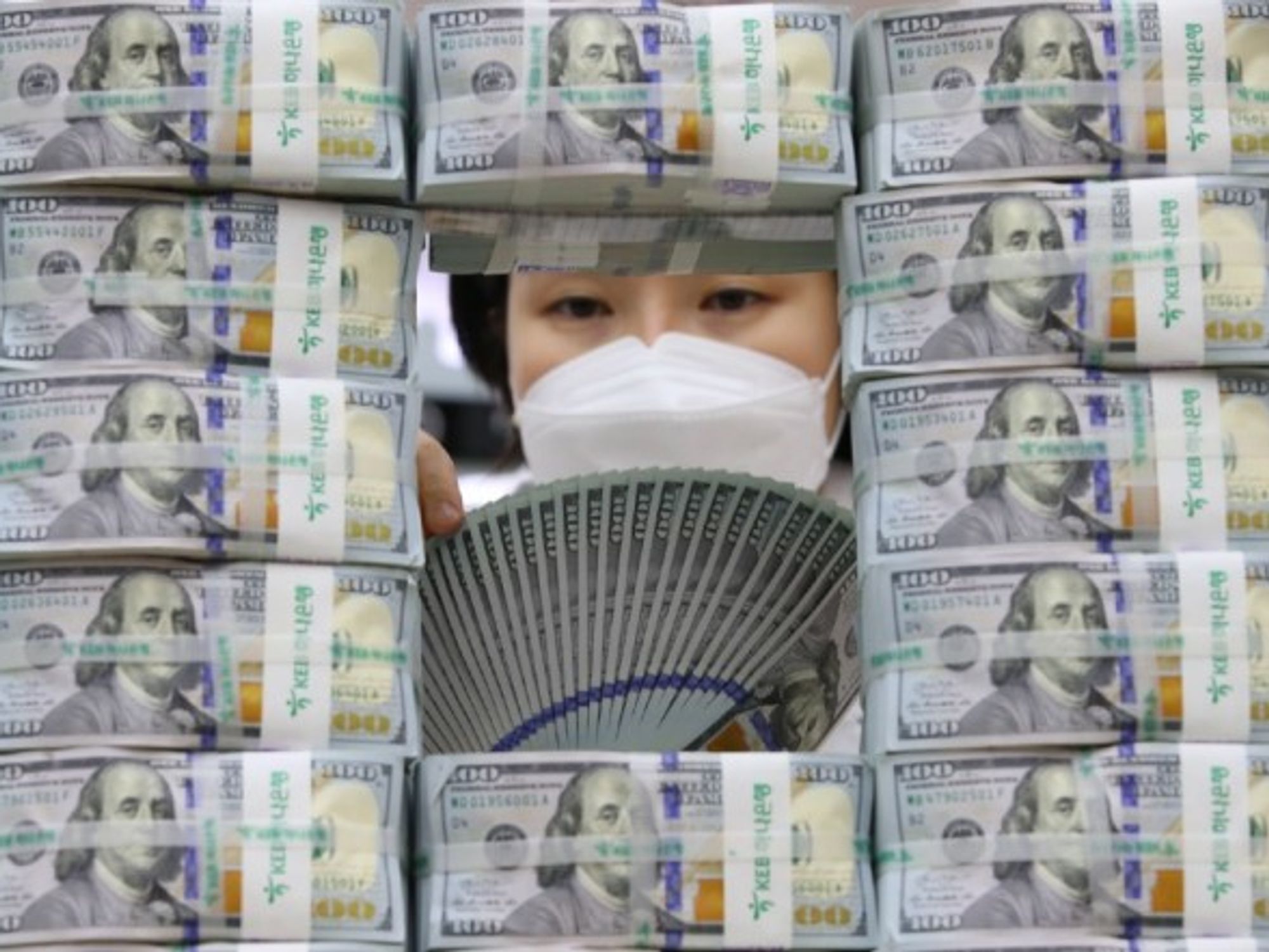 A bank clerk scrutinizes $100 US banknotes in Seoul, South Korea.