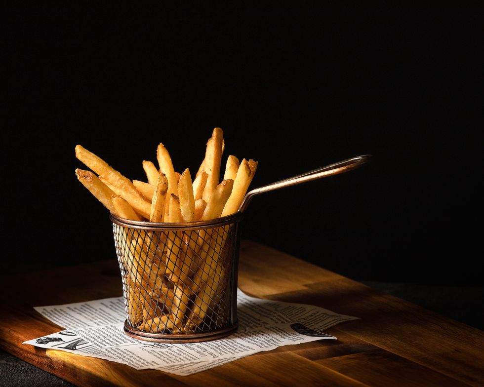 A basket of French fries on a wooden table.