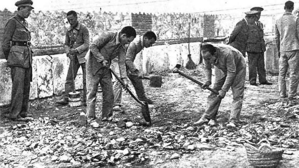 A black and white image depicting prisoners labouring, overseen by uniformed men