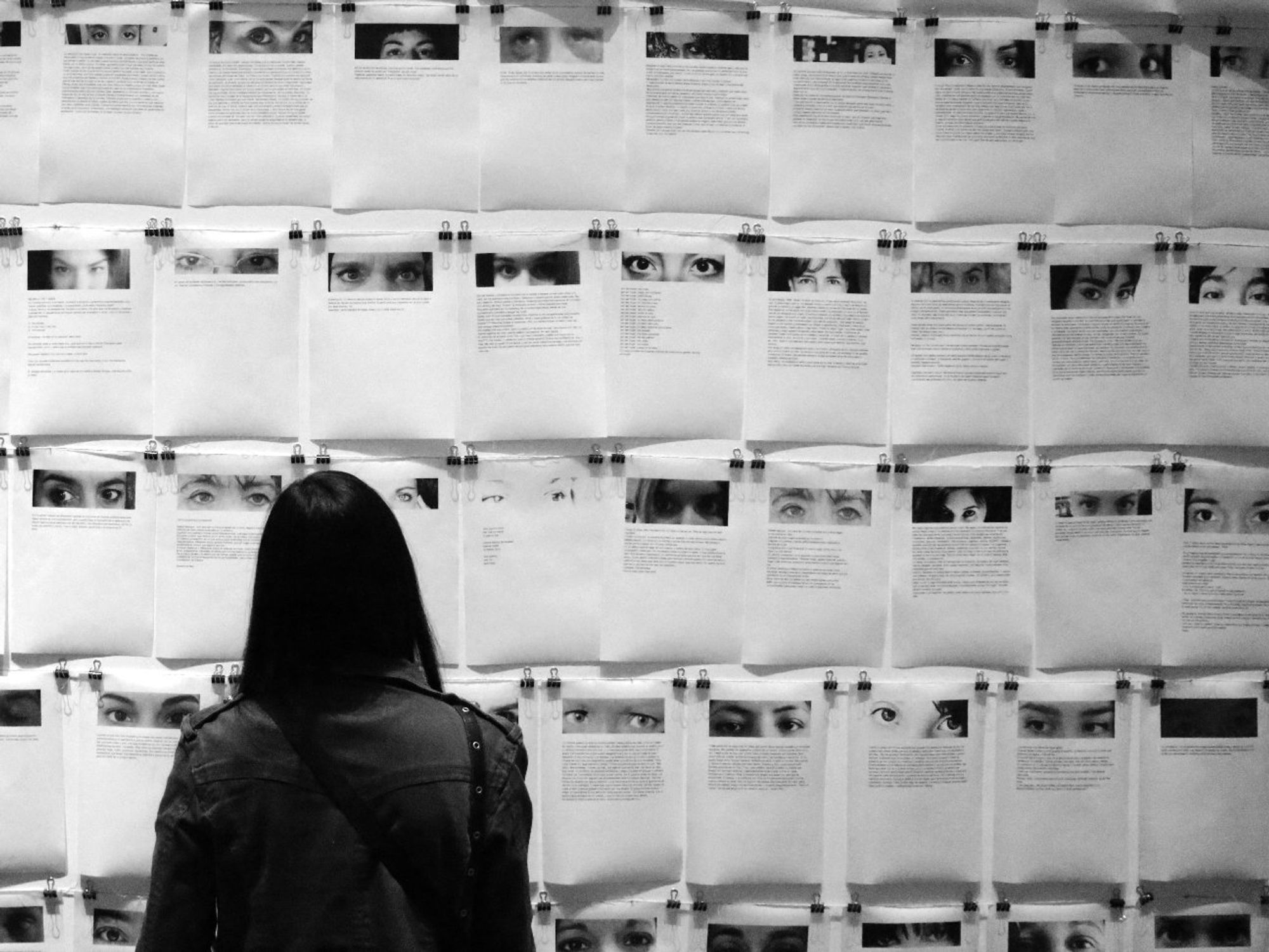 A black and white image of a woman looking at a memorial wall in Argentina.