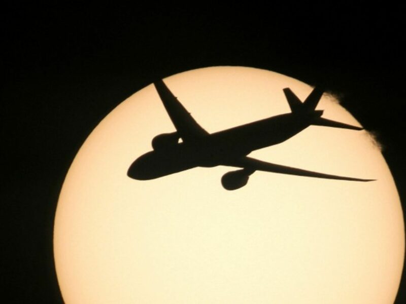 A Boeing 777 is silhouetted against the sun
