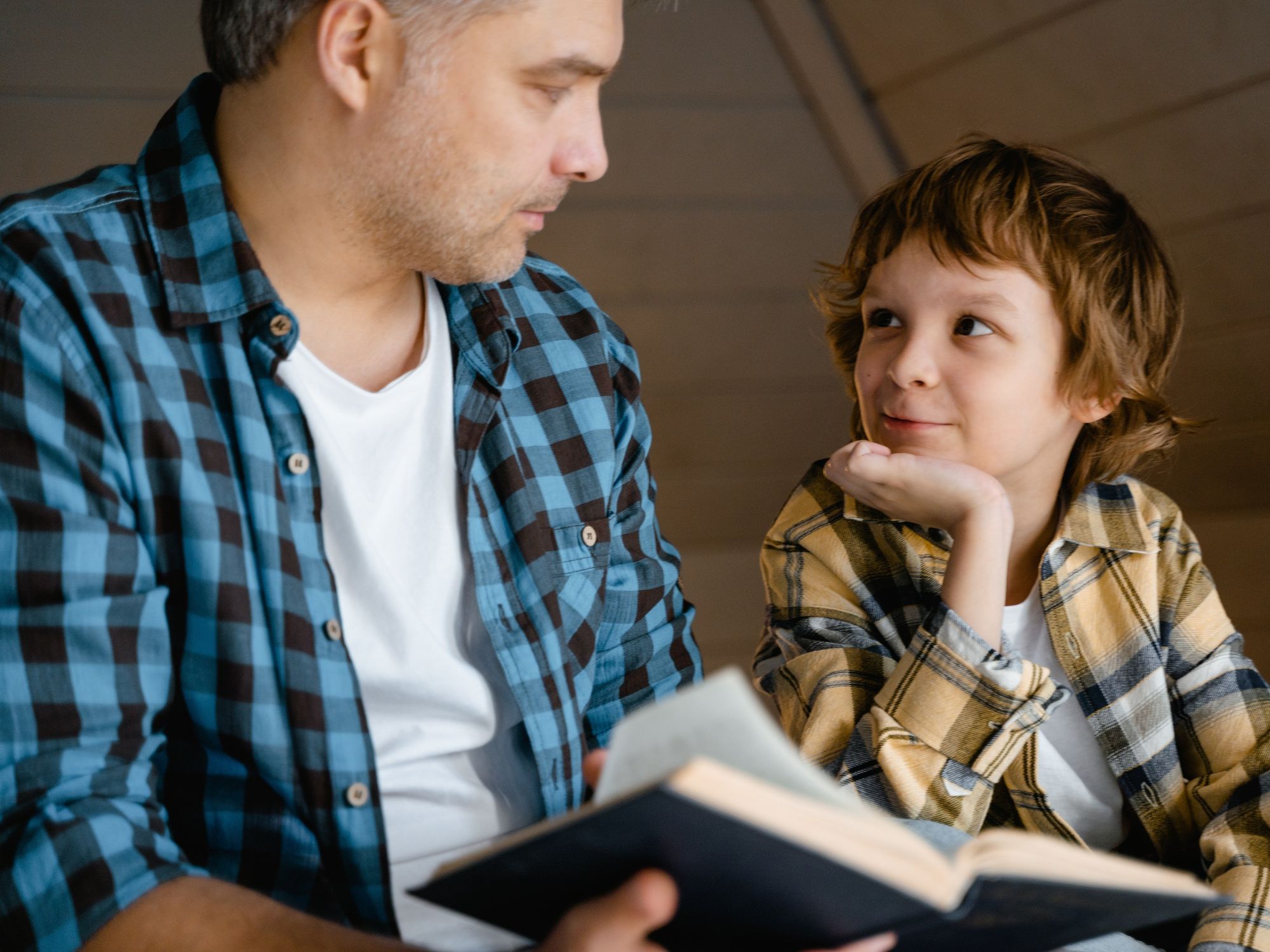 A Boy Looking up at a Man Holding a Book