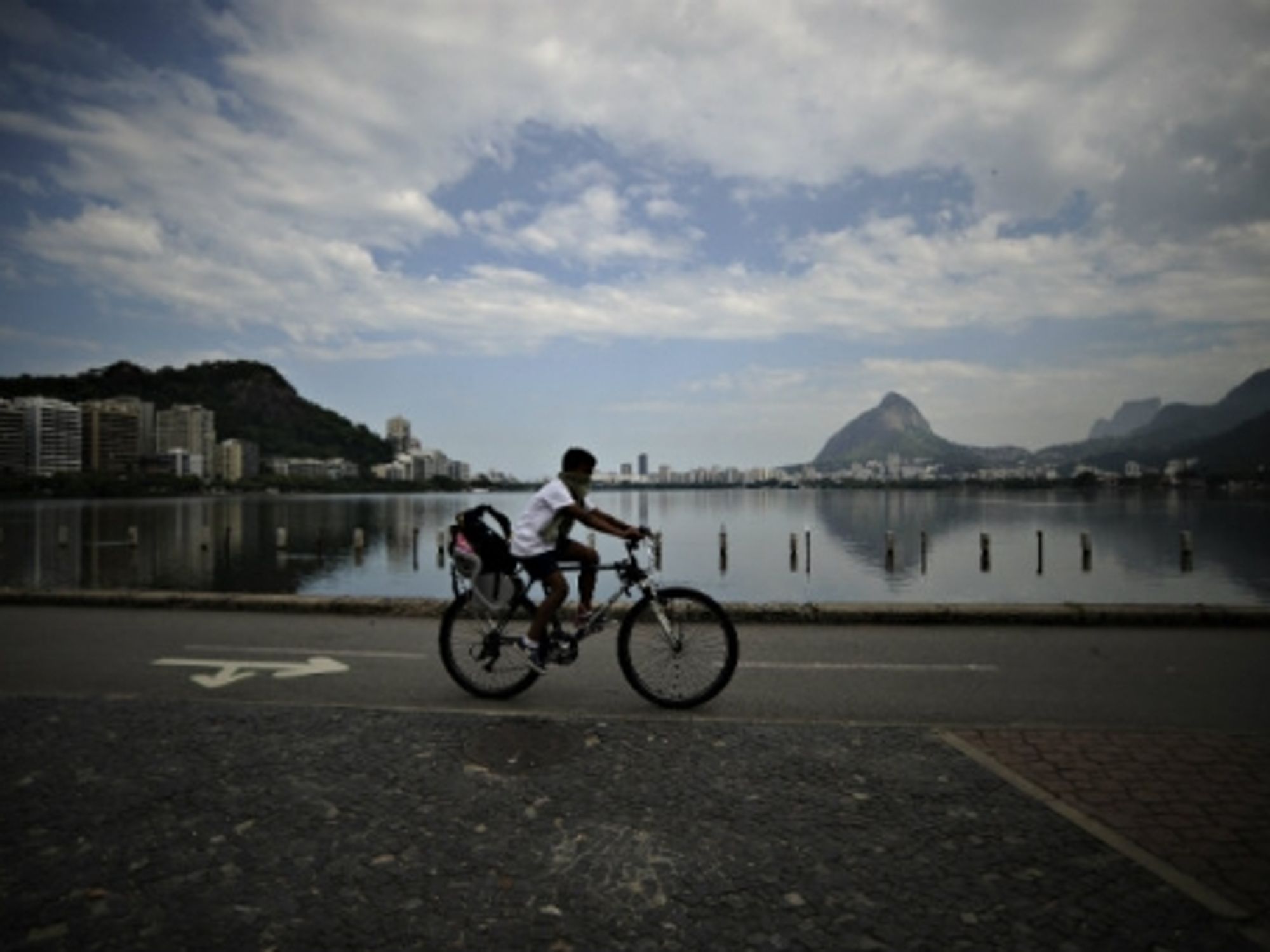 A boy peddles past the polluted Rodrigo de Freitas lagoon slated to be the site of sailing events at Rio 2016.