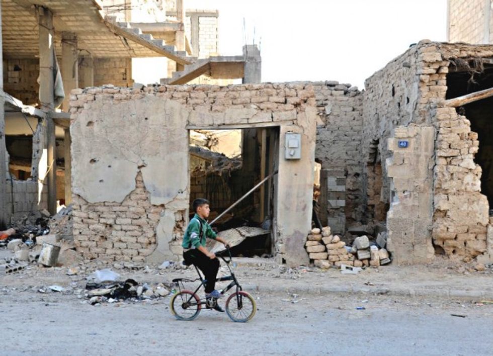 A boy rides a bicycle amid rubble in Homs