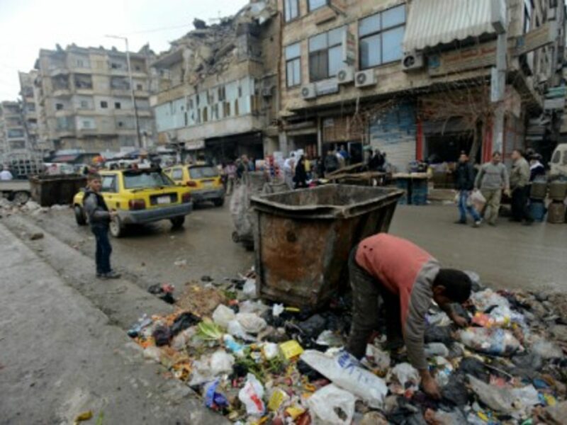 A boy searches in a pile of garbage for something to eat in Aleppo.