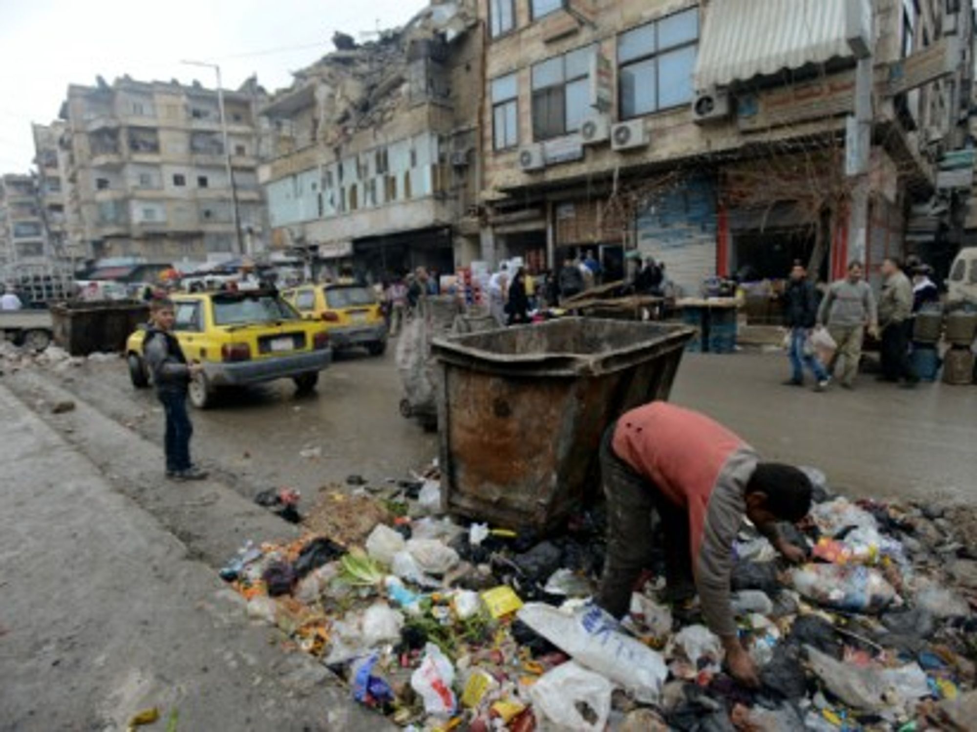 A boy searches in a pile of garbage for something to eat in Aleppo.