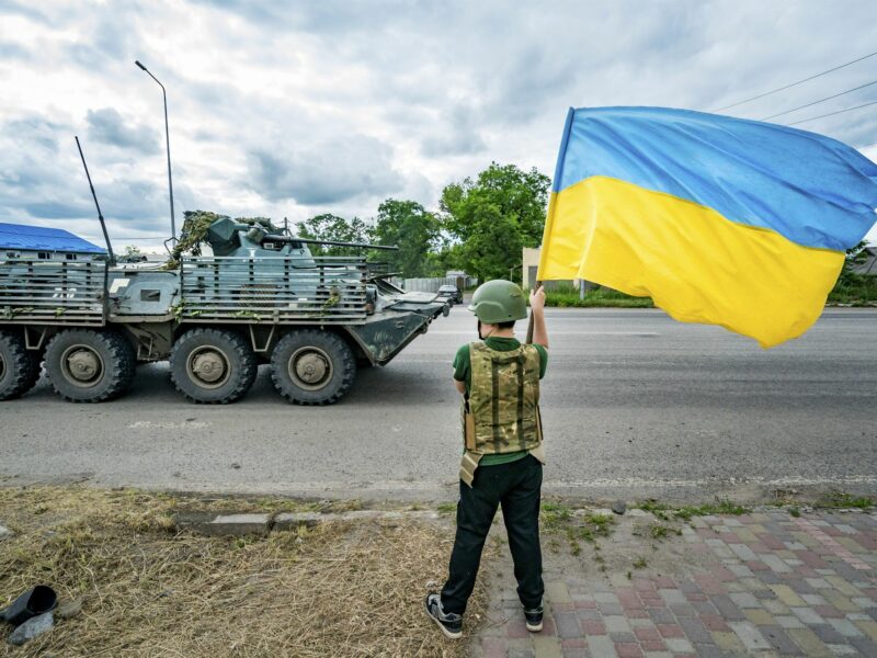 A boy waves a Ukrainian flag as a Ukrainian armored vehicle drives by