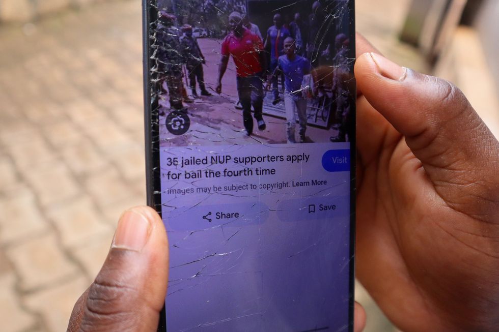 A broken phone screen shows an image with the caption "35 jailed NUP supporters apply for bail for the fourth time"
