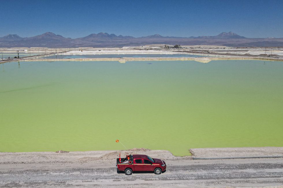 A car drives along infront of a brine pool in the desert