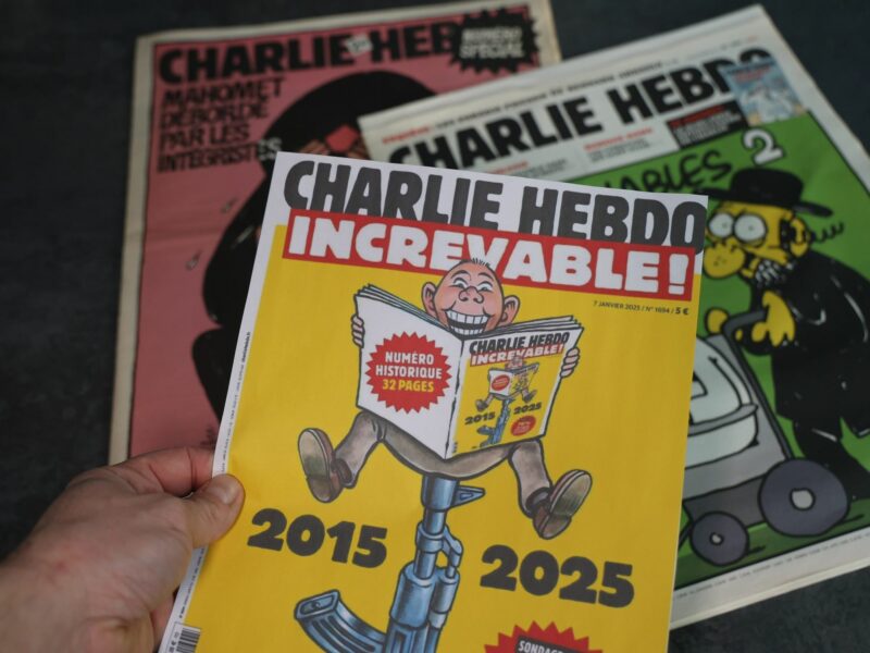 A Charlie Hebdo magazine reads "Increvable" with the years 2015-2025 on the cover.