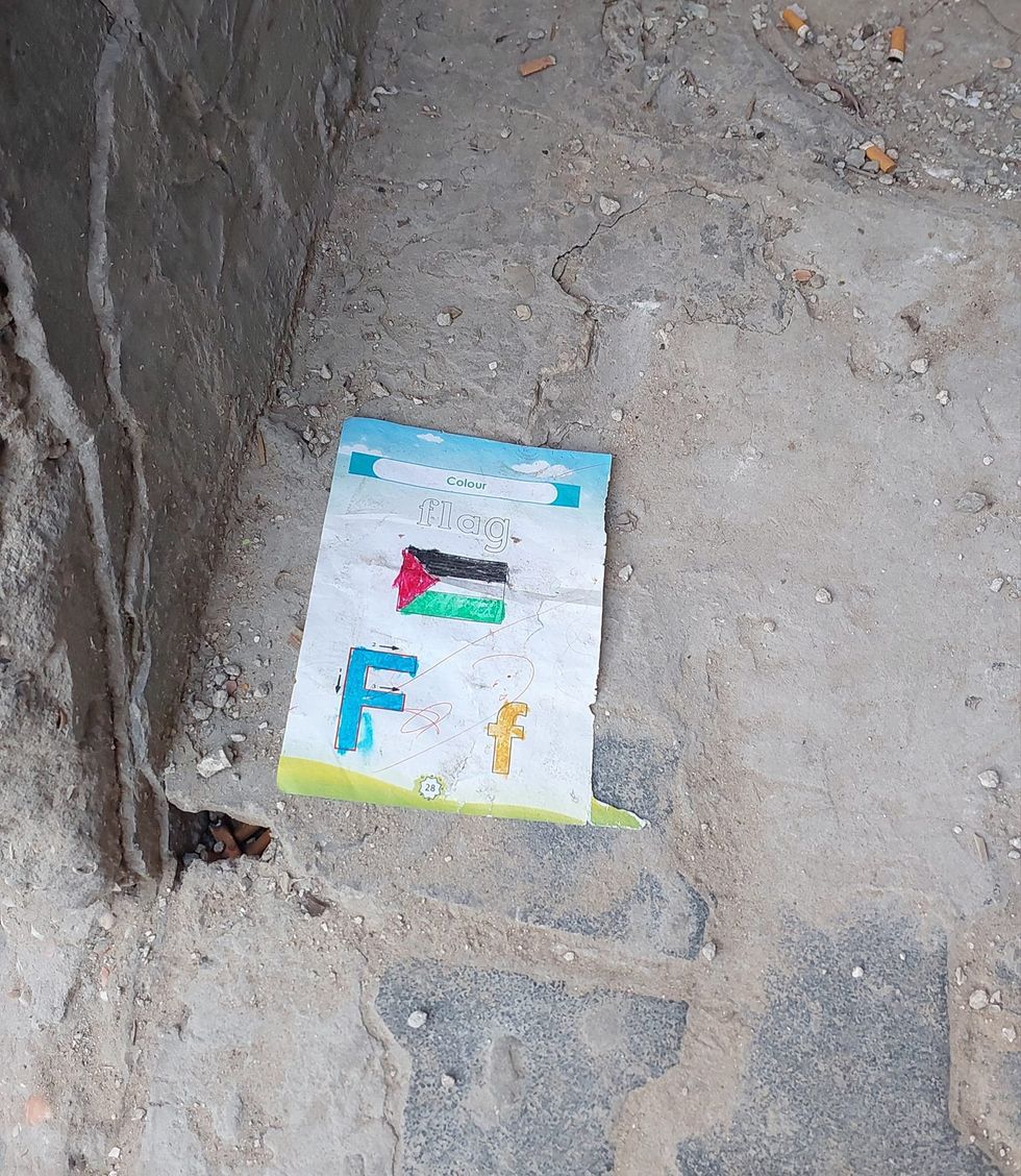 A childs coloring page of the Palestinan flag on the ground.