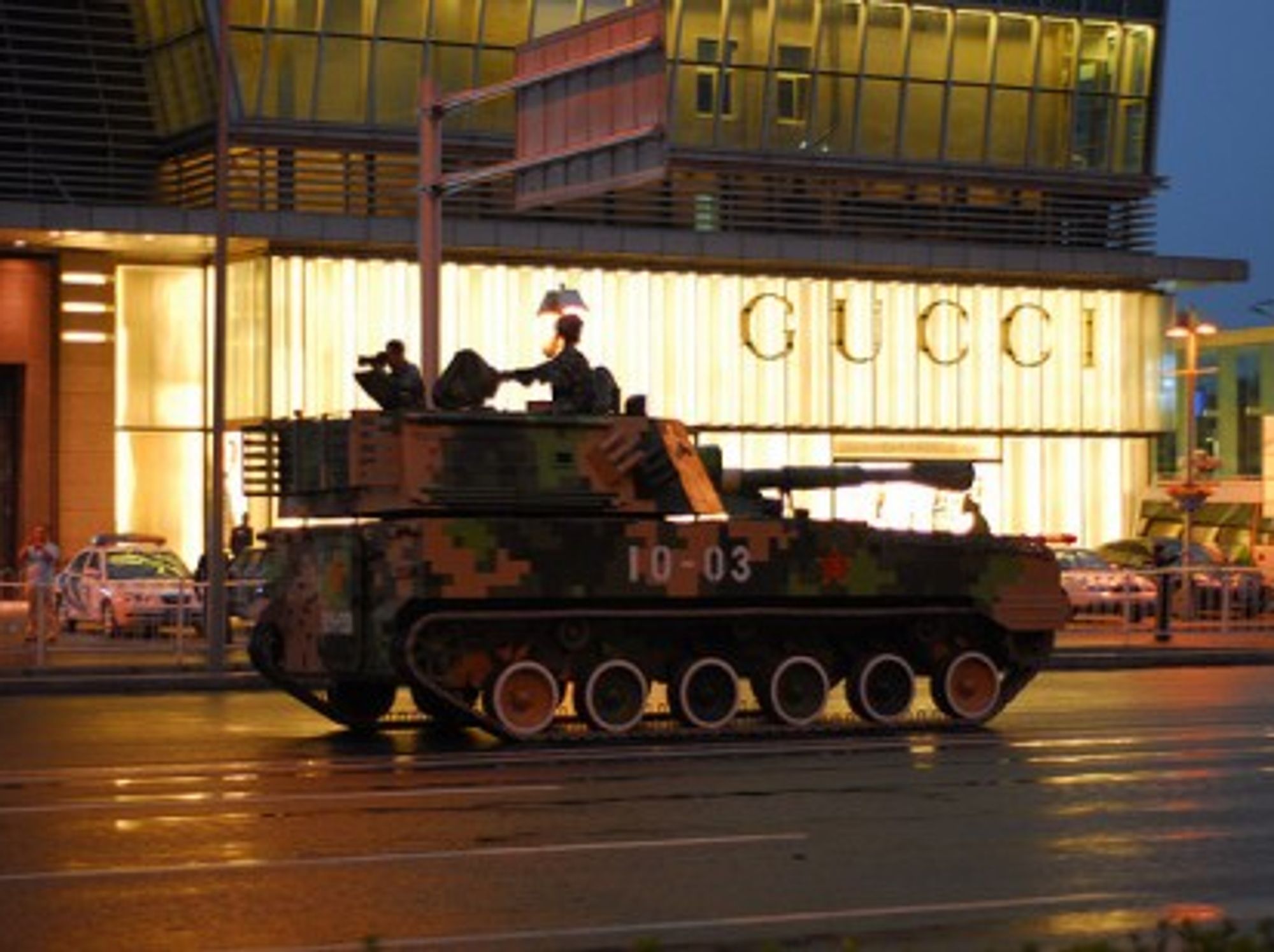 A Chinese tank rolls past a Gucci store in Beijing (gadgetdan)