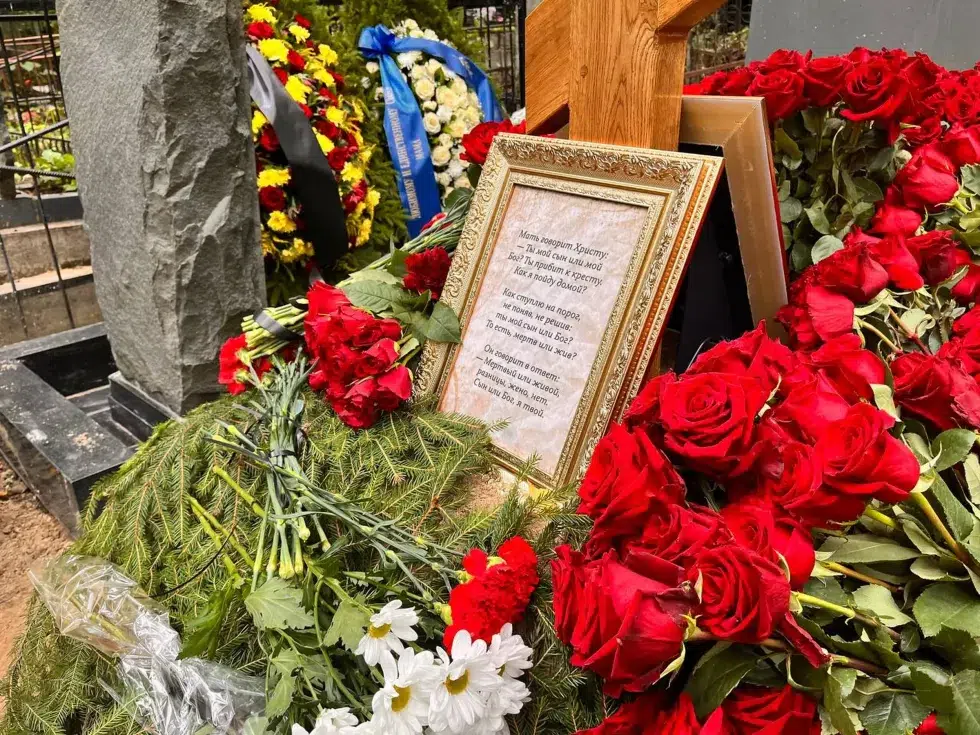 A close up photograph of Prigozhin's grave, showing roses and a plaque written in Russian.