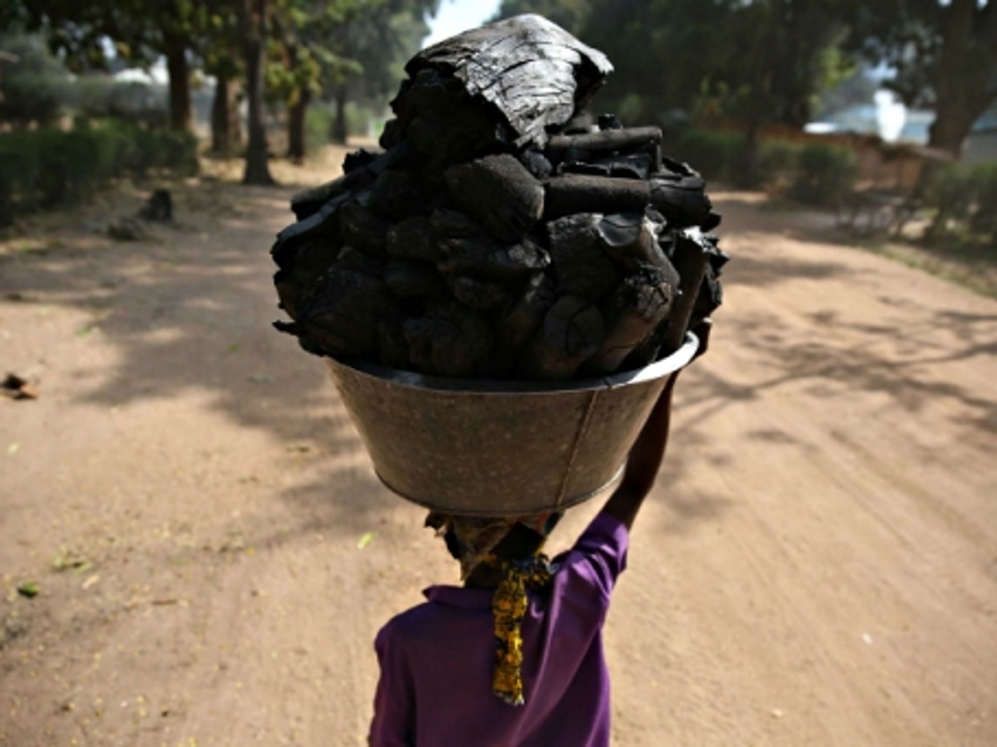 A Congolese woman carrying a basin full of coal