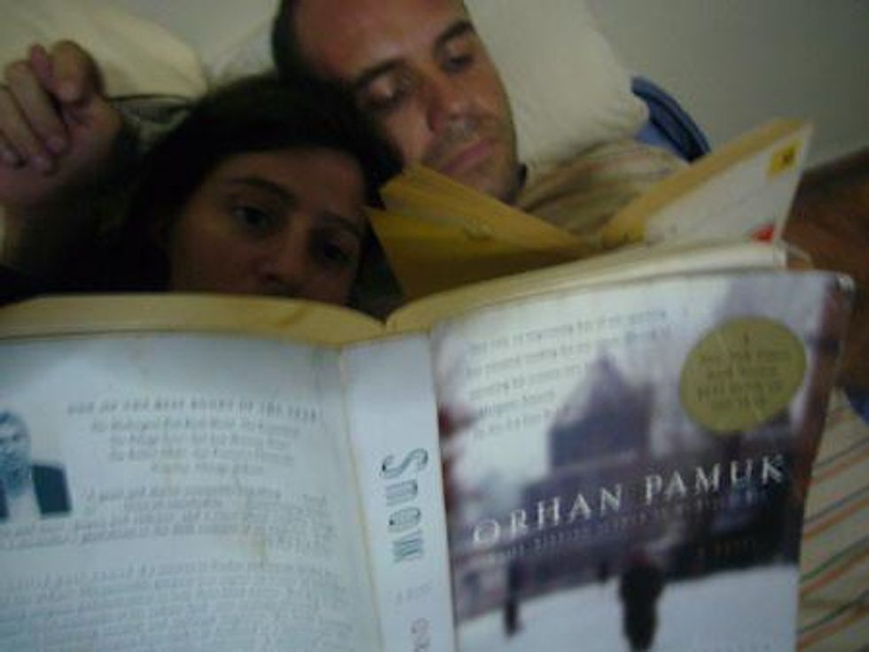 A couple reading a book by Orhan Pamuk in bed.