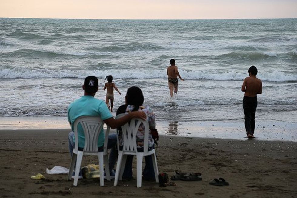A couple sits on the Caspian Sea shore.